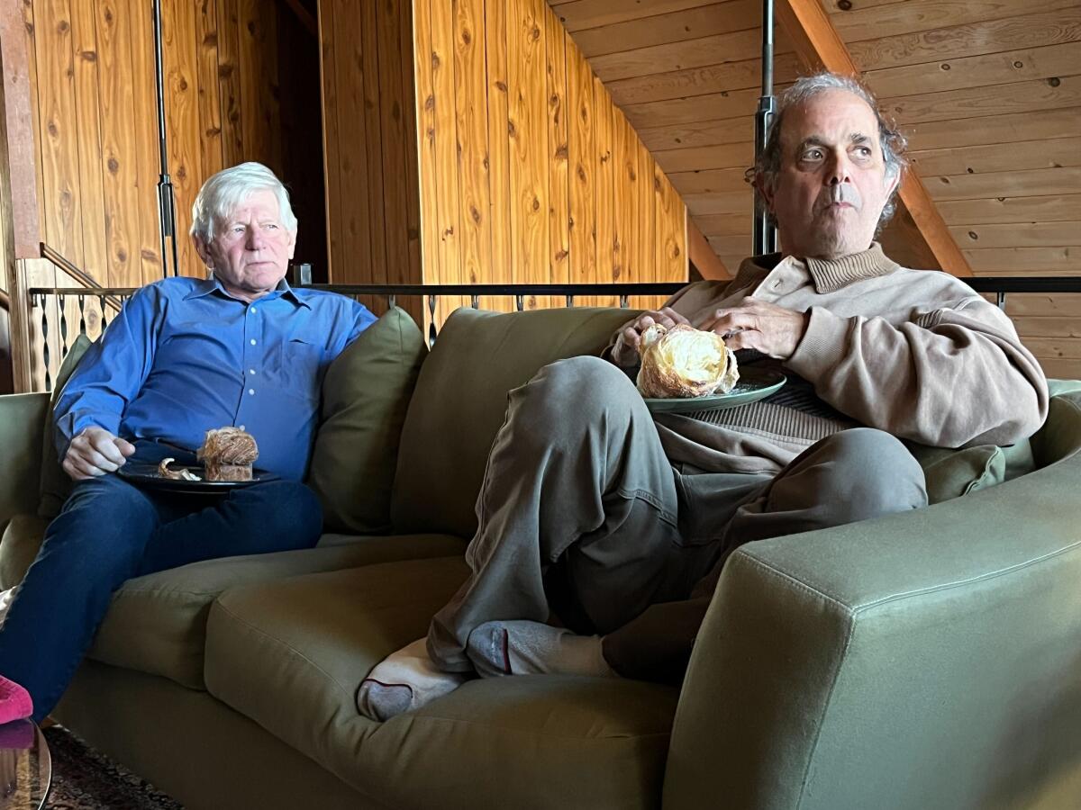 Friends Jack Minckler and Gary Himelfarb sit on a couch staring to the right.