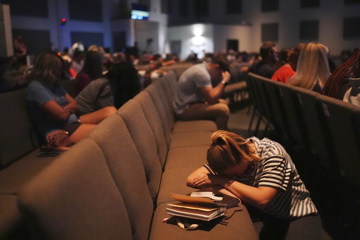A woman lays her head down on a seat during a vigil at CenterPoint Church for Charlie Kirk in Orem, Utah.