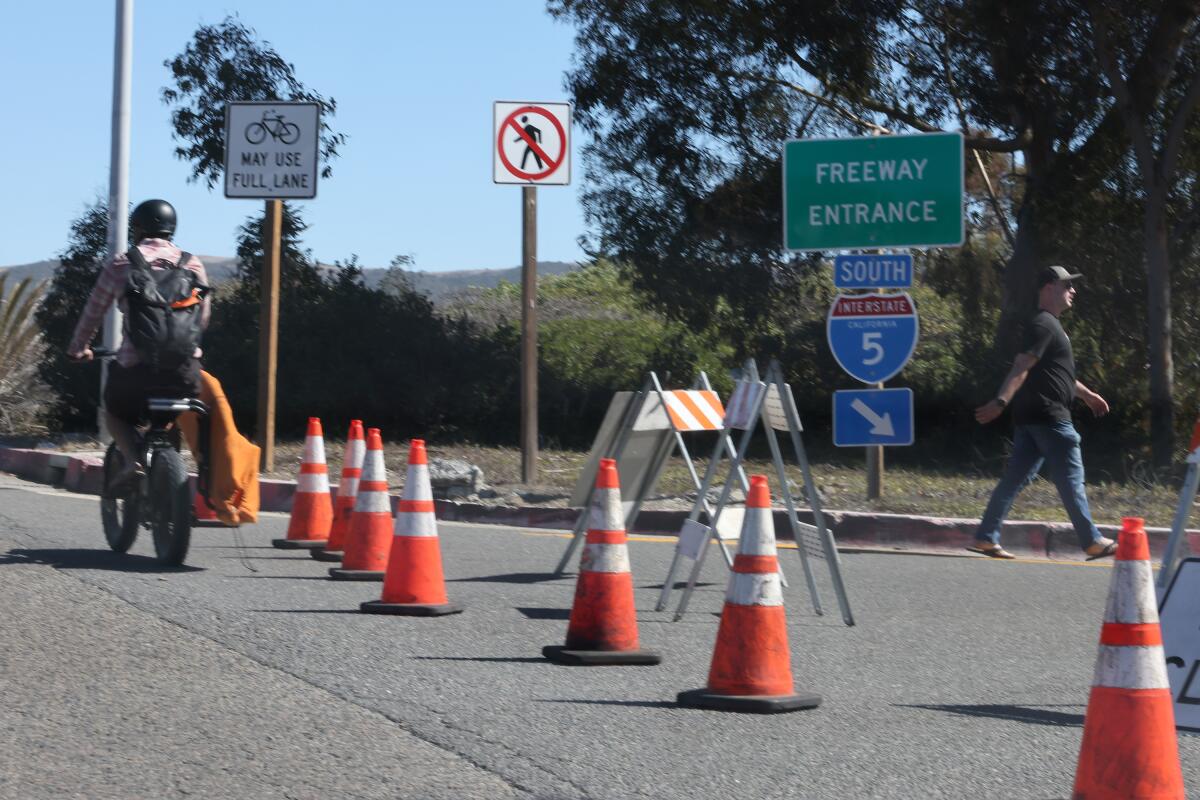 A cyclist maneuvers around safety cones signaling that Interstate 5 is closed on Saturday.